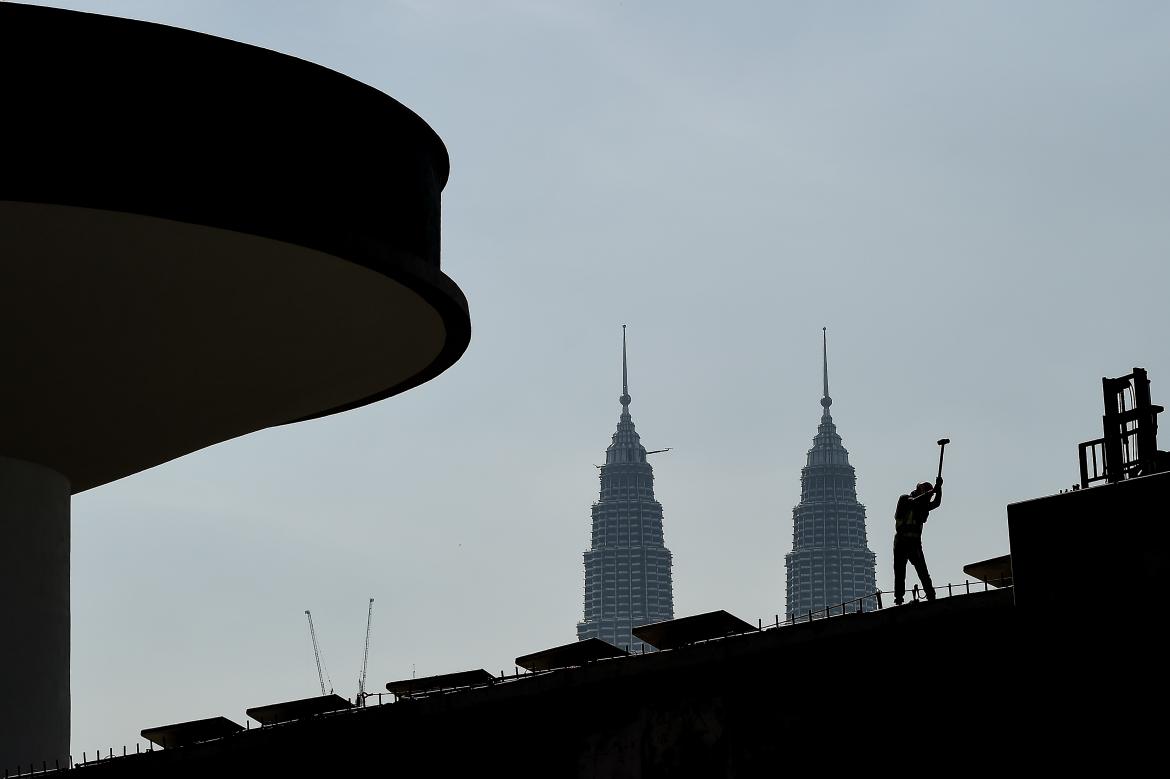 A worker is silhouetted against the Petronas Twin Towers in Kuala Lumpur, Malaysia's capital city. (AFP)