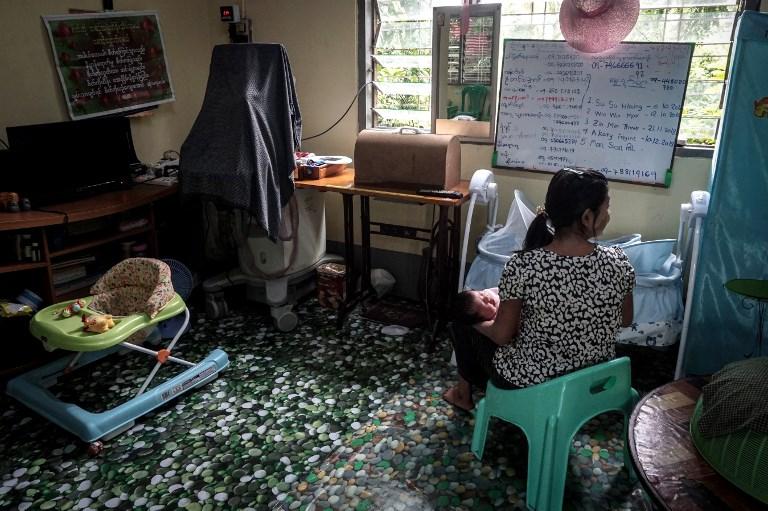 Aye Mar (not her real name), eight months pregnant and unmarried, takes care of a baby of another single mother taking refuge at the Myint Mo Myittar Single Mothers' Foundation in Yangon. (AFP)