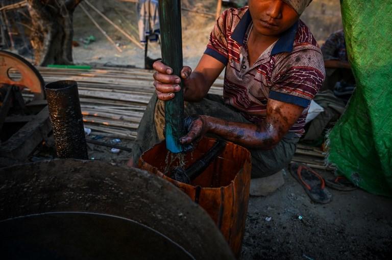 A worker operates a machine to extract crude oil from a well at an informal oil field in Minhla Township. (AFP)