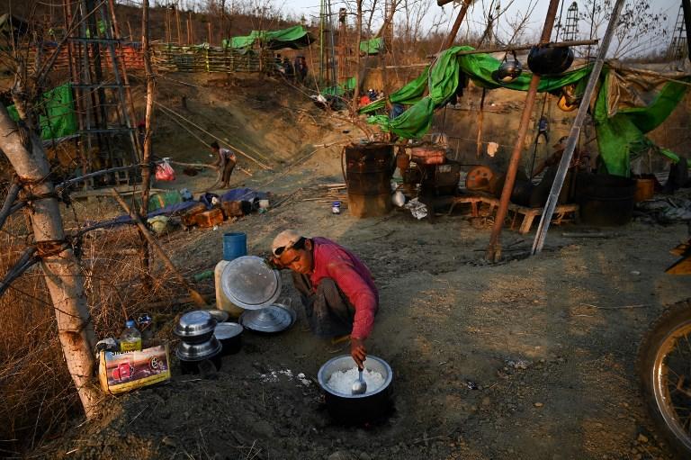 A worker cooks a meal beside an oil rig at an informal oil field in Minhla Township. (AFP)