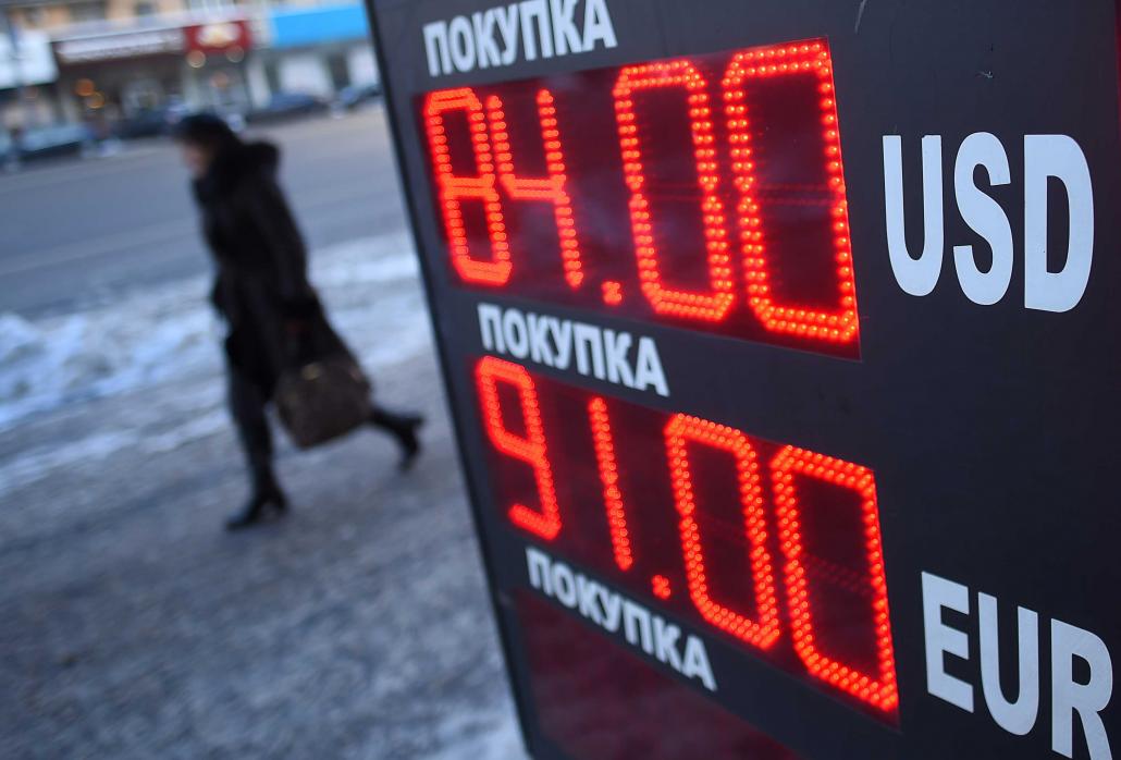 A woman walks past a board listing foreign currency rates. (AFP)