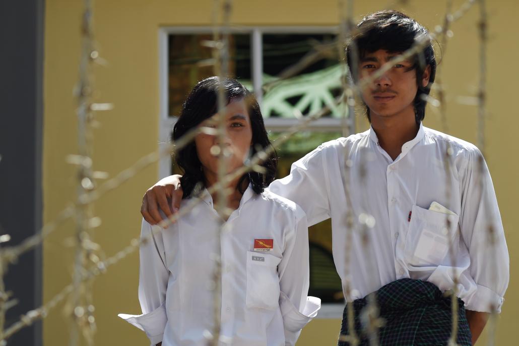 Ma Myo Htet Paing, left, and Ko Lwin Ko Ko Aung, both 20, stand behind a barbed wire fence outside the court house in Thayawady town before their trial for participating in the National Education Law protest in Letpadan. (Romeo Gacad / AFP)