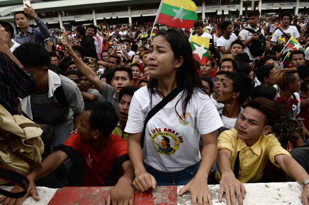 Migrants from Myanmar hold national flags as they wait at a market in Samut Sakhon province, west of Bangkok, on June 23 for the arrival of State Counsellor Daw Aung San Suu Kyi. (AFP)