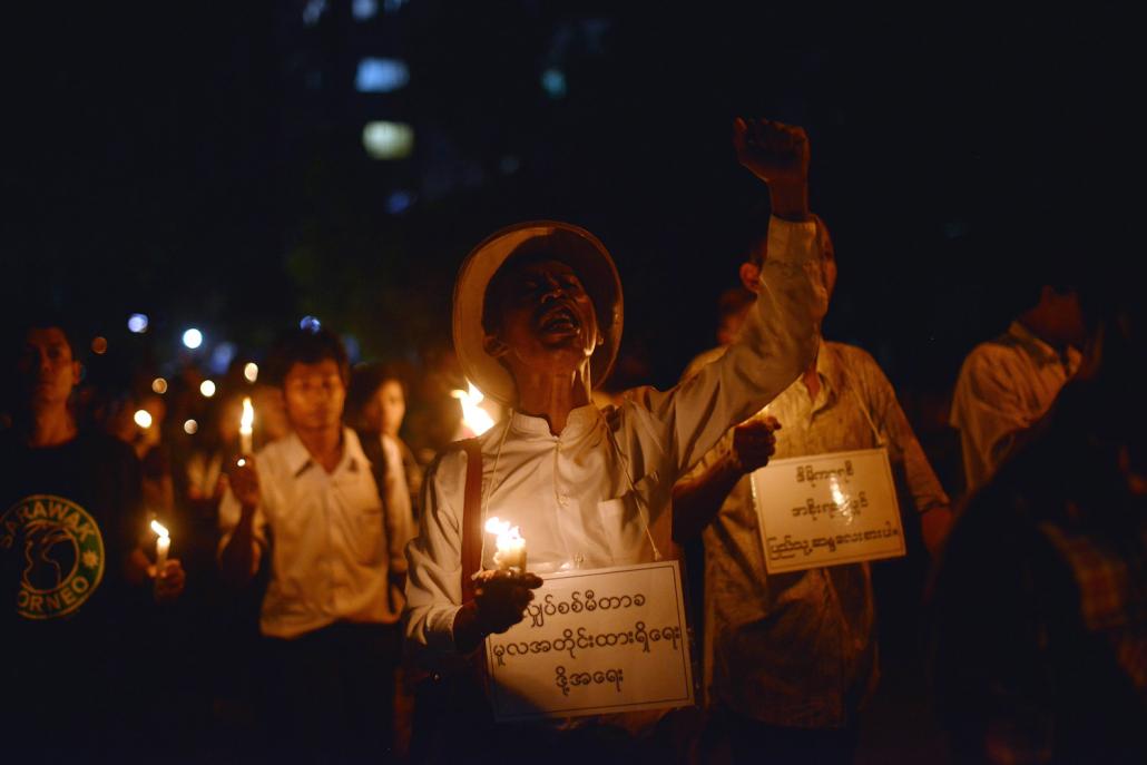 Protesters hold candles and shout slogans as they stage a protest against electricity price increases in Yangon in November 2013. (AFP)