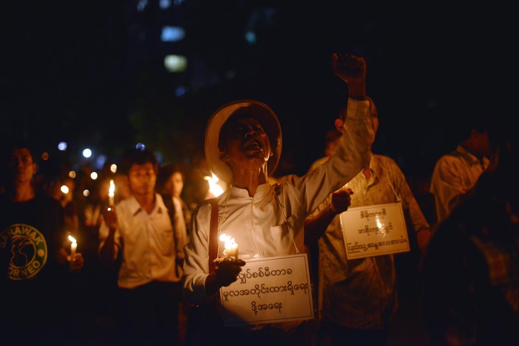 Protesters hold candles and shout slogans as they stage a protest against electricity price increases in Yangon in November 2013. (AFP)