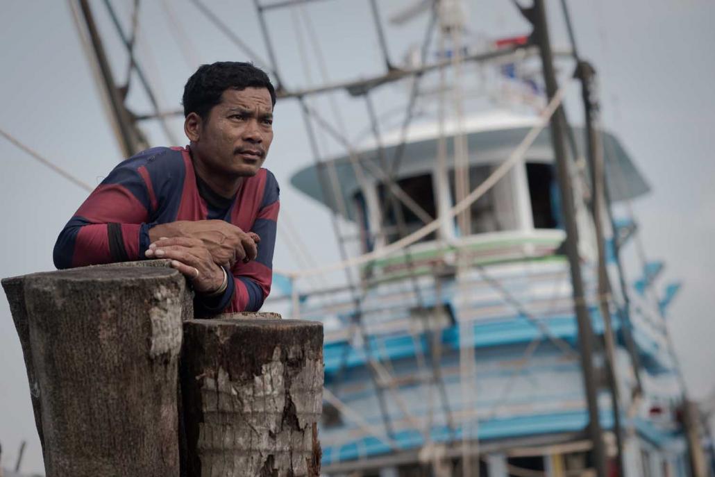 A Myanmar migrant worker stands in front of a fishing boat in Thailand's Ban Nam Khaem village. Many migrants use hundi networks to send money back to their relatives in Myanmar. (AFP)