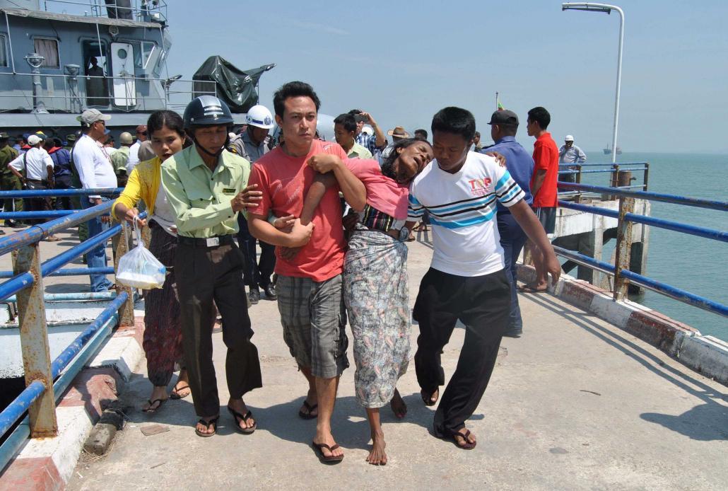 အောင်တံခွန် (၃) နစ်မြုပ်မှုတွင် အသက်ဘေးမှ လွတ်မြောက်လာသူတစ်ဦးအား ကျောက်ဖြူဆိပ်ကမ်းသို့ ခေါ်ဆောင်လာသည်ကို ၂၀၁၅ ခုနှစ်၊ မတ် ၁၄ ရက်နေ့က တွေ့ရစဉ်။ ဓာတ်ပုံ- အေအက်ဖ်ပီ