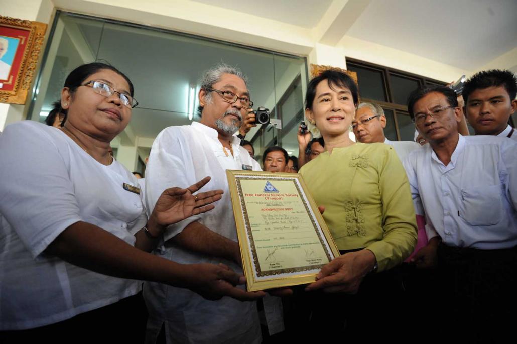 Daw Aung San Suu Kyi accepts an acknowledgement letter at a ceremony to commemorate the 10th anniversary of the Free Funeral Service Society group in Yangon in April 2011. (AFP)