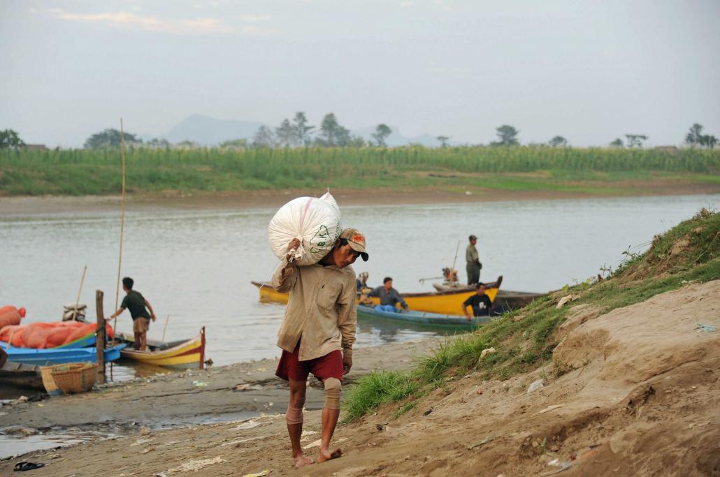 A man carries a bag of supplies on the bank of the Thanlwin River at Hpa-an, the capital of Kayin State. (AFP)