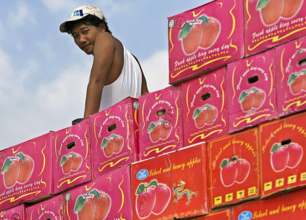 A worker sits on boxes of apples for export to China at the border town of Muse. (AFP)