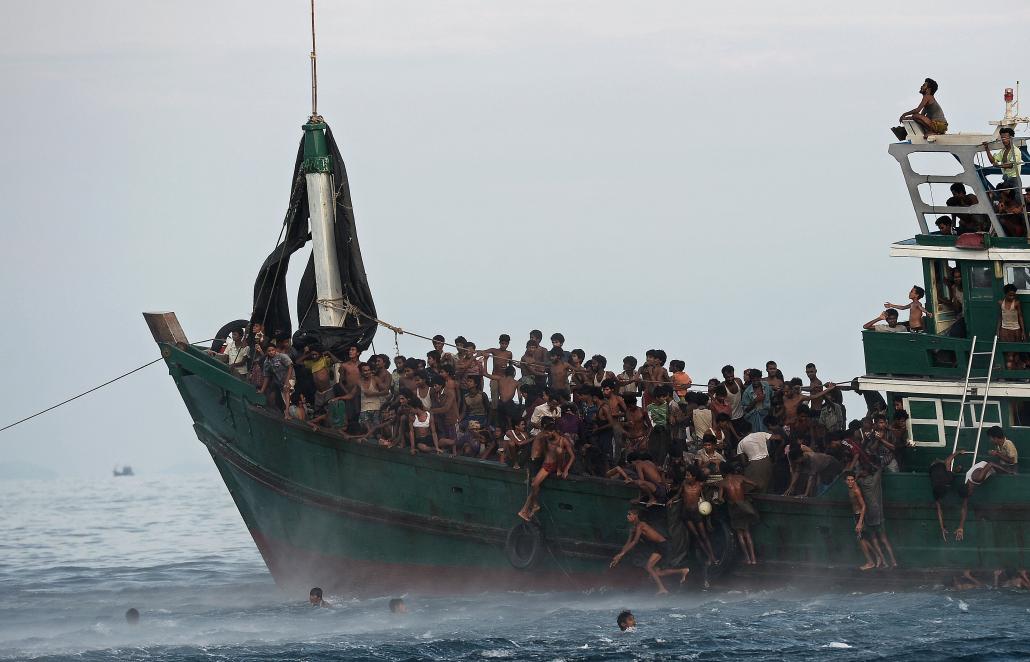 Rohingya migrants jump to collect food supplies dropped by a Thai army helicopter from a boat drifting in Thai waters off the southern island of Koh Lipe in the Andaman Sea in May 2015. (AFP)