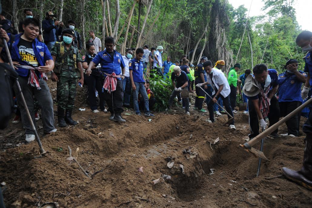 Rescue workers and forensic officials dig out the skeletons of human trafficking victims from shallow graves at an abandoned jungle camp in Thailand's southern Songkhla province, May 2015. (AFP)