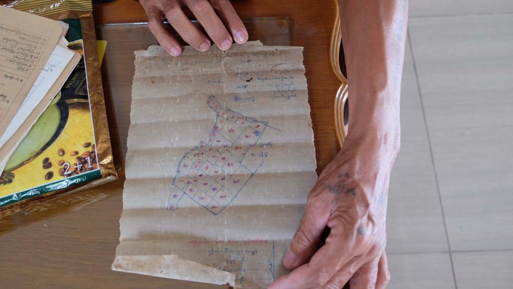 Farmer U Myint Swe holds a map showing plots that were confiscated by YCDC for a cemetery (Kyaw Ye Lynn | Frontier)