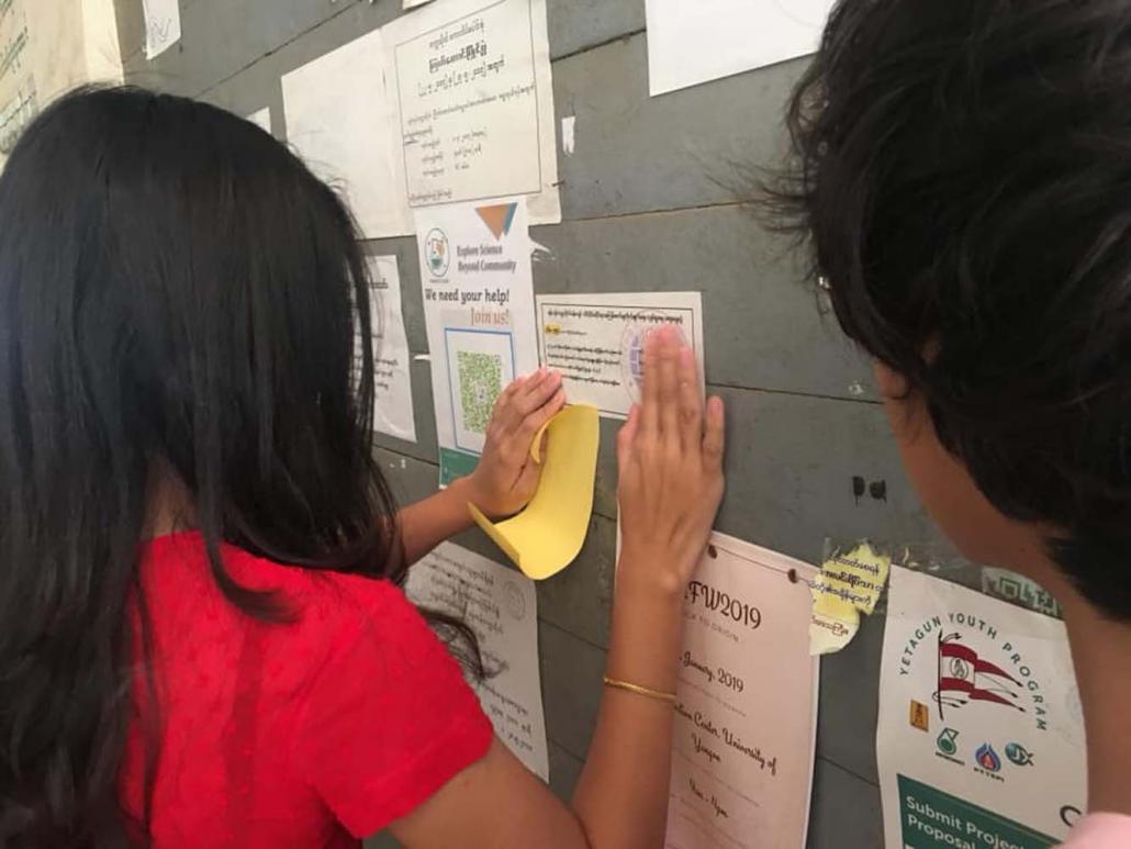 Students post stickers at Yangon University to promote an event aimed at combating sexual harassment on campus. (Supplied)