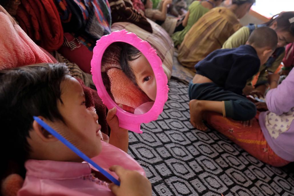 A child passes the time by grooming herself at the Bobour Yakadar Nursing Home in Kyaukme, where about 350 people from five villages are taking shelter. (Brennan O'Connor / Frontier)