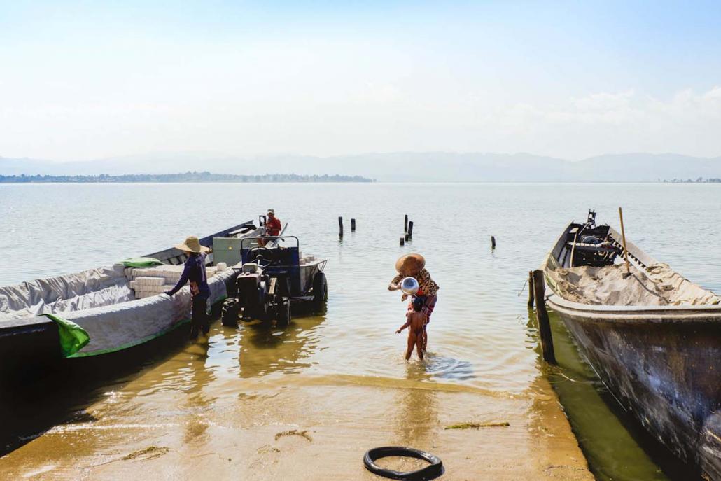 A woman washes her child on the shore of Pekon. (Dominic Horner | Frontier)