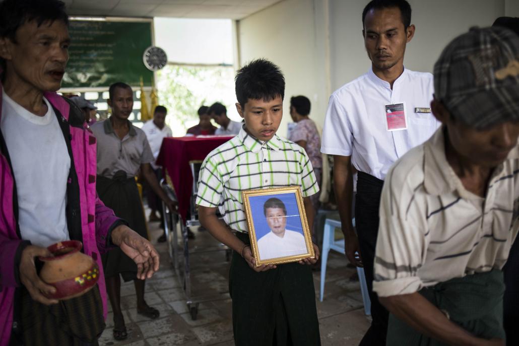 One of U Aung Kyaw Linn's sons carries a photo of him on the day of his funeral. (Ann Wang / Frontier)