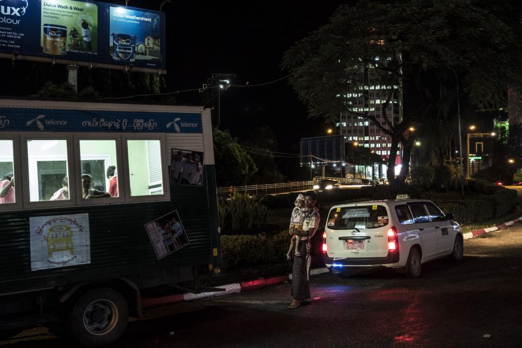 A parent stands outside a mobile education bus across from Yangon's Thamada Cinema. (Andre Malerba / Frontier)