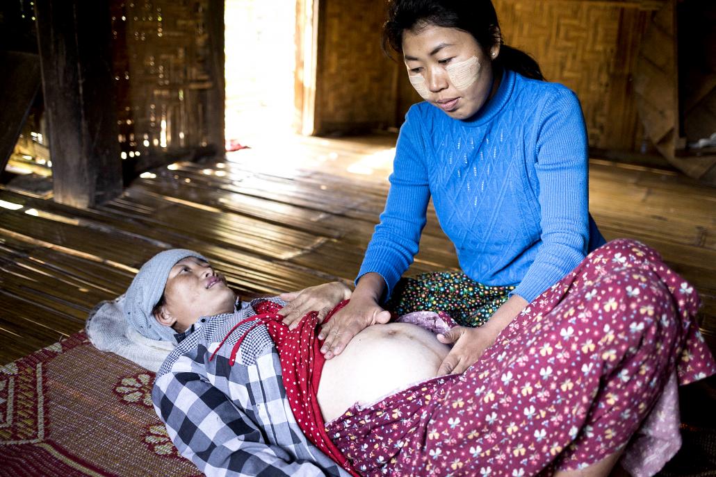 Pongya Nin Ngamdan, 32, is 36 weeks’ pregnant. Here she is examined by the midwife Daw Phyu Phyu Htwe at her house in Putao's Zino village. (Ann Wang / Frontier)