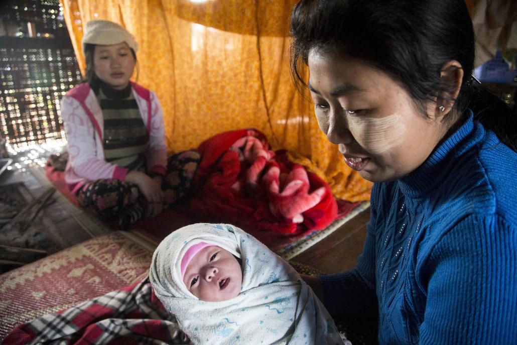 Midwife Phyu Phyu Htwe holds the one-month-old baby of Garu Nang Baisan, 16. (Ann Wang / Frontier)