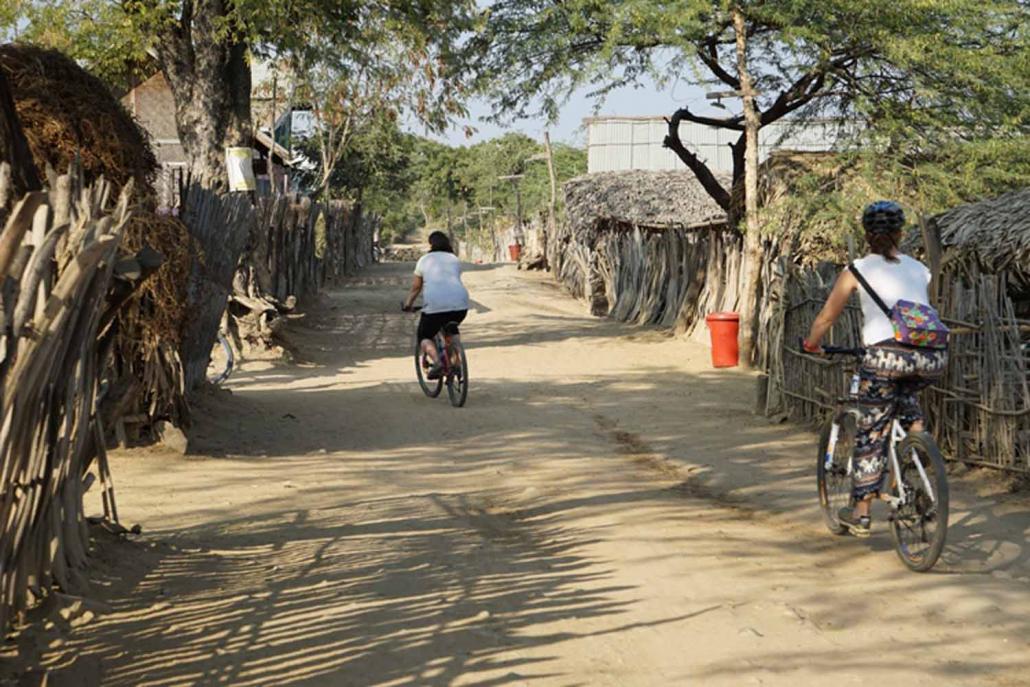 Tourists participating in a community-based tourism project ride bicycles through a Myaing Township village. (Supplied)