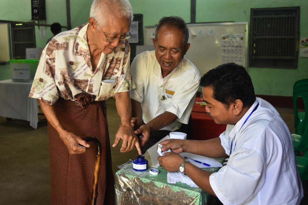 An elderly voter has a finger inked by a polling officer at a station in Tarmwe, Yangon. (Kyaw Lin Htoon | Frontier)