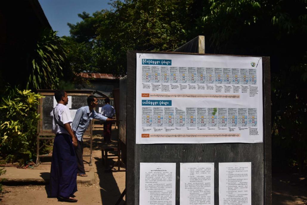 Voters check names their names on the voter list before entering a polling station in Tarmwe. (Kyaw Lin Htoon | Frontier)