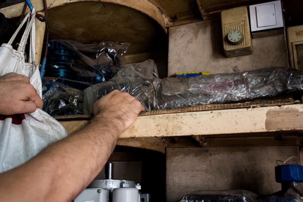 A vendor shows a chainsaw hidden behind other commercial products in a hardware shop in Mandalay. (Ann Wang | Mongabay)