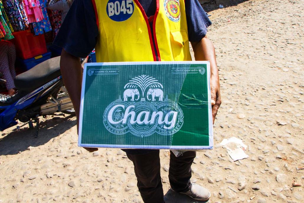 A worker carries a box of Thai-made Chang beer at Bayintnaung Market in Myawaddy Township. (Thuya Zaw | Frontier)