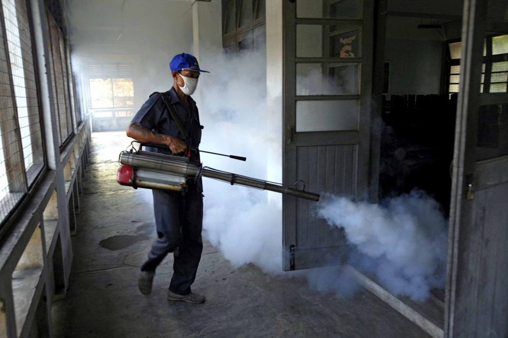 A health worker fumigates classrooms in Yangon. (Khin Maung Win / AFP)