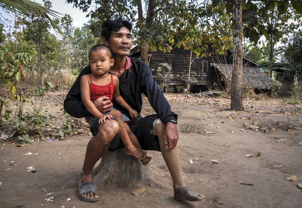 A disabled DKBA veteran holds his daughter at Thitsar Aye Myaing village near Myaing Gyi Ngu. (Kyaw Lin Htoon | Frontier)