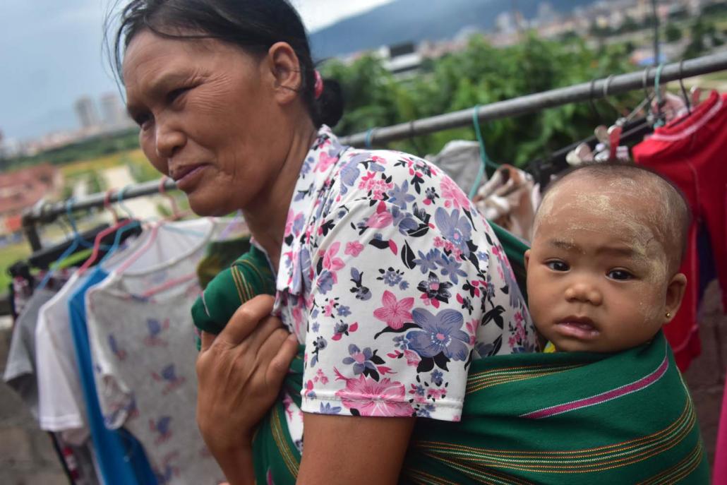 A migrant worker from central Myanmar walks through Muse with her granddaughter slung over her back. (Kyaw Lin Htoon | Frontier)