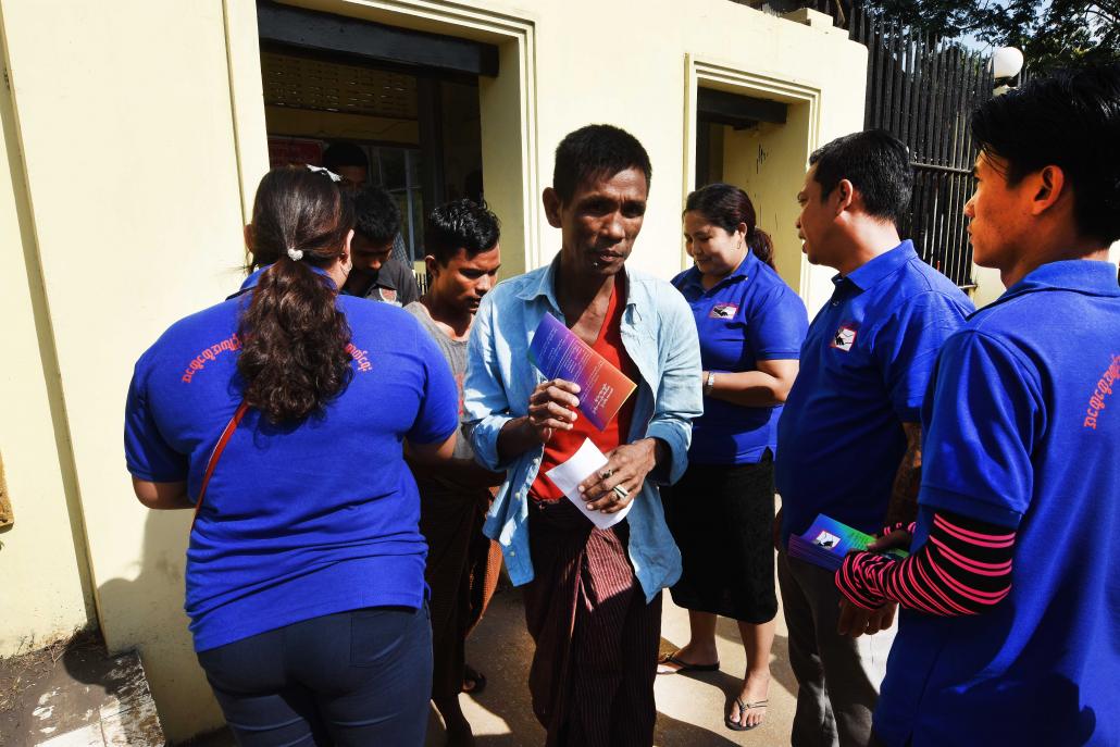 Volunteers with the General Prisoners' Rehabilitation Myanmar hand out pamphlets to family visitors leaving Insein Prison. (Steve Tickner | Frontier)