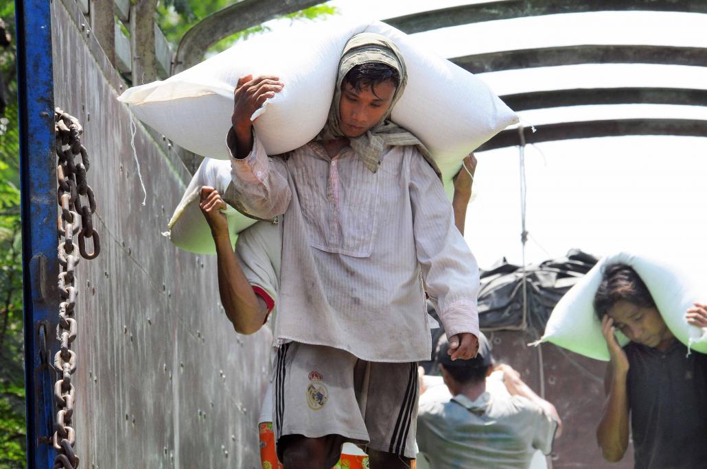 Workers unload bags of rice at Yangon port. The cost of transporting rice from the farm to port can be twice as high in Myanmar compared to neighbouring countries like Thailand and Vietnam due to poor infrastructure. (Steve Tickner / Frontier)