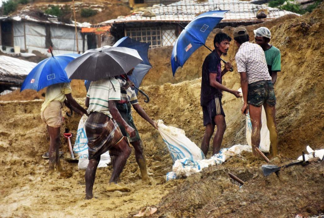 Rohingya men work to remove an unstable slope at the Balukali refugee camp. (Steve Tickner | Frontier)