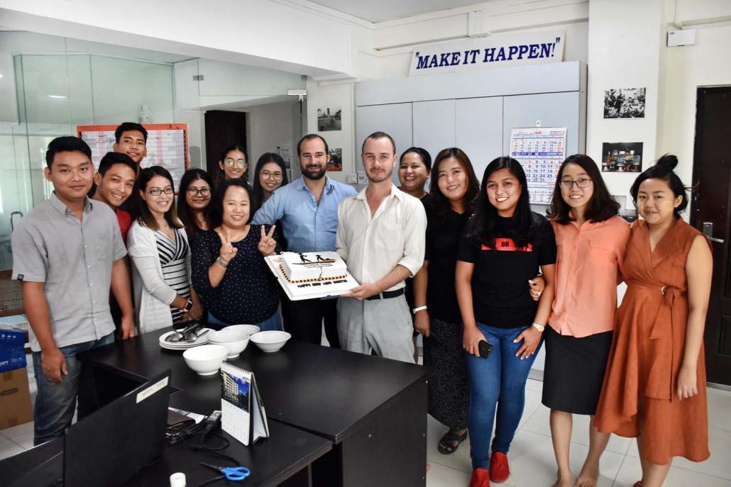 Mr Bertie Lawson, surrounded by members of the Sampan team, holds a cake with the Sampan Travel logo. (Steve Tickner | Frontier)