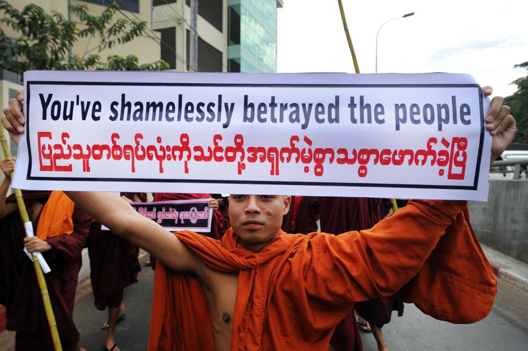 A monk holds a vinyl protest sign during a protest march organised by Ma Ba Tha in Yangon, February 2015. (Steve Tickner / Frontier)