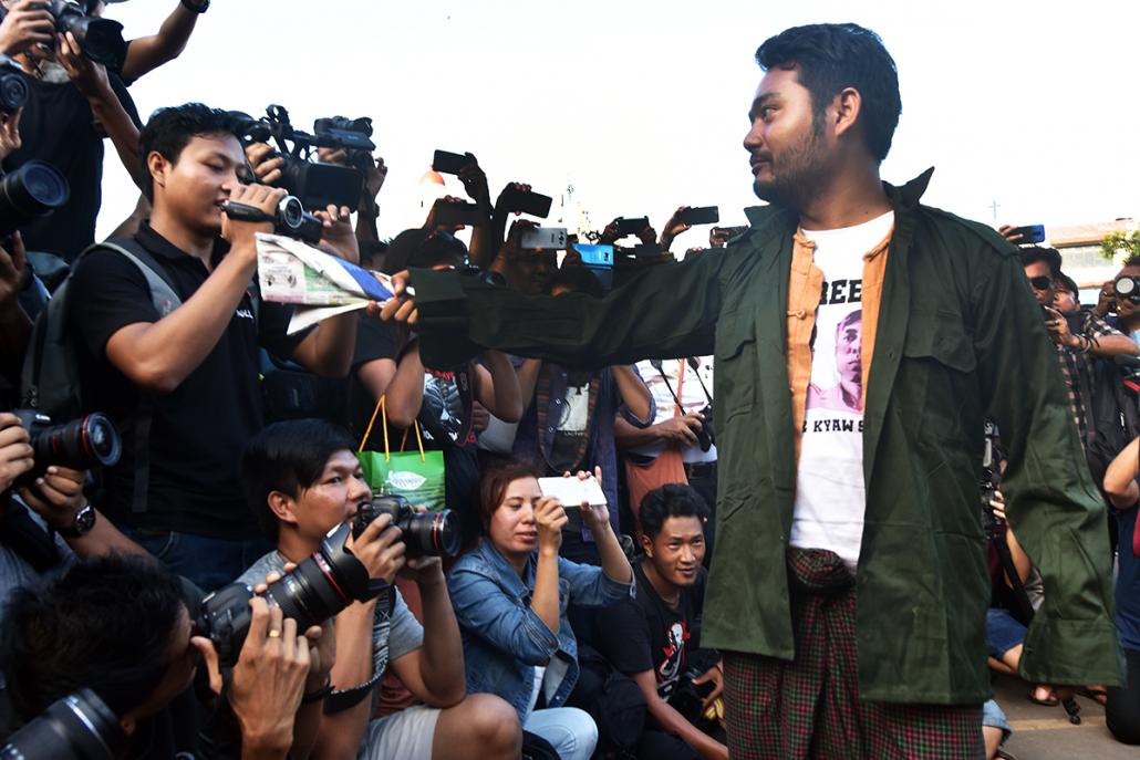 Activist Maung Saungkha brandishes a copy of state-run paper Kyemon during a short performance. (Steve Tickner | Frontier)