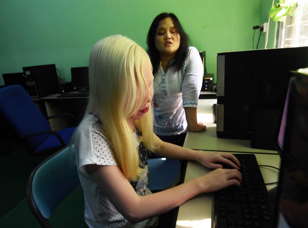 Blind student Ma Phyu Phyu Wn learns to use a computer equipped with voice command software under the tuition of Naw Htee Ywar, a former student. (Steve Tickner | Frontier)