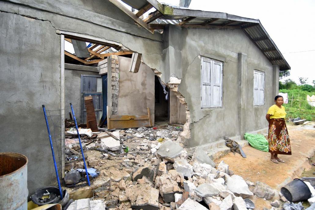 The wife of a retired Tatmadaw officer stands in front of her home in Lashio Township on August 18 after it was damaged during fighting. (Steve Tickner | Frontier)