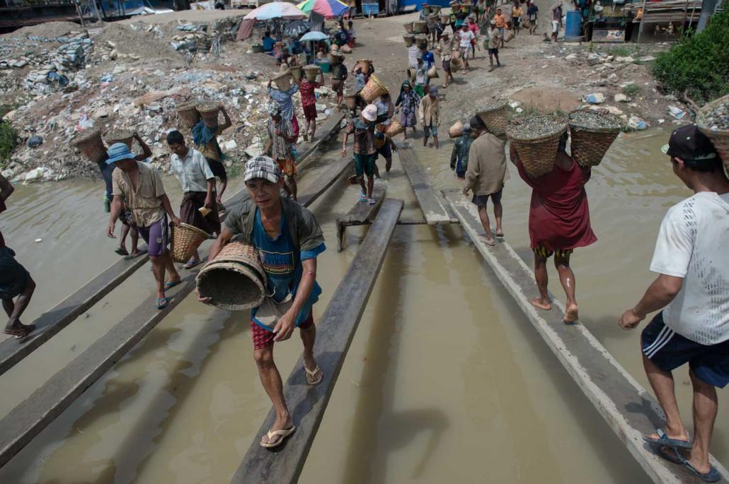 ရန်ကုန်မြို့တွင် မော်တော်ပေါ်မှ ကျောက်စရစ် သယ်ချနေသည့် အလုပ်သမားများကို တွေ့ရစဉ်။ ဓာတ်ပုံ - အေအက်ဖ်ပီ