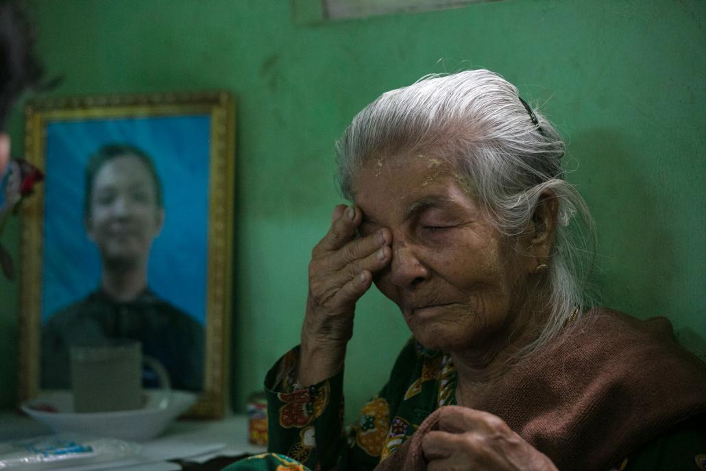 Ko Kyaw Zin Win's grandmother sits next to a portrait of her grandson during his funeral in Yangon on June 25. (AFP)