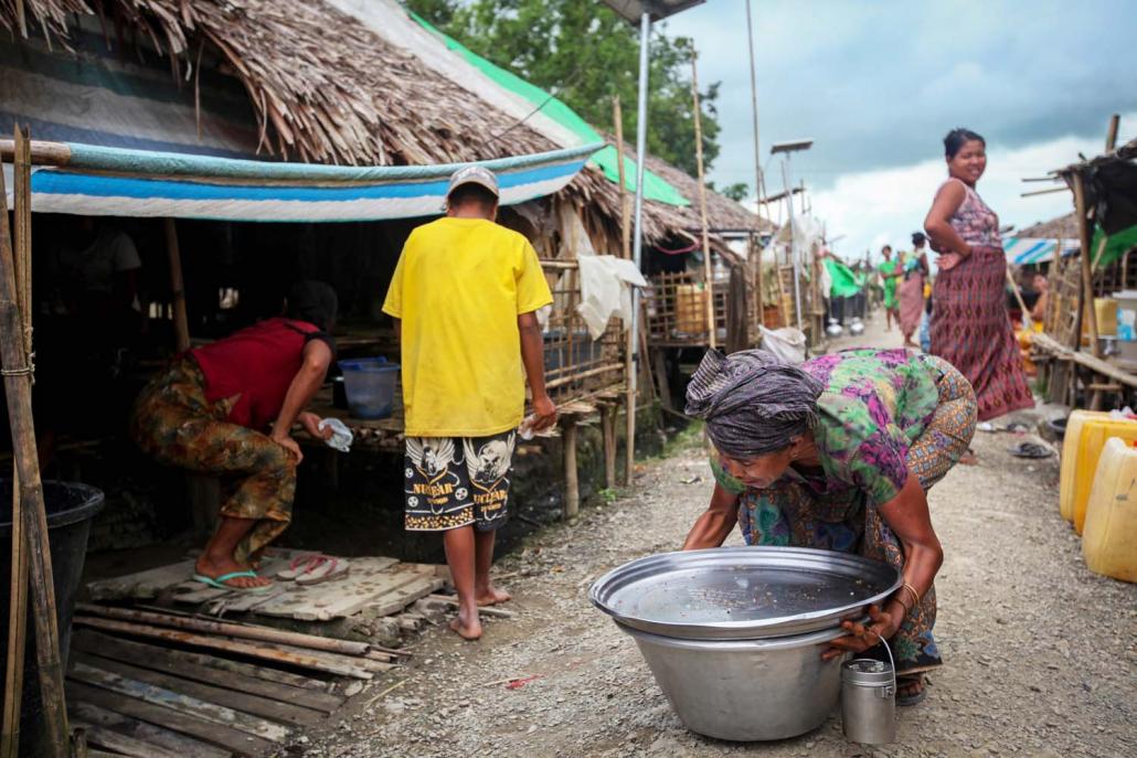 An old woman in Taing Nyo IDP camp clears up her wares after selling snacks to camp residents. (Kyaw Lin Htoon | Frontier)