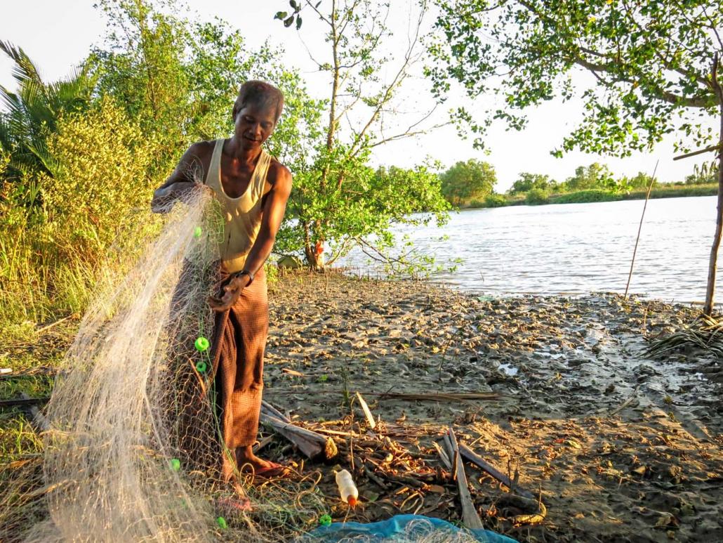 A fisherman carefully folds his net in Ka Nyin Kone village in Labutta Township. Catches in the area have been steadily declining, residents say. (Kyaw Lin Htoon | Frontier)