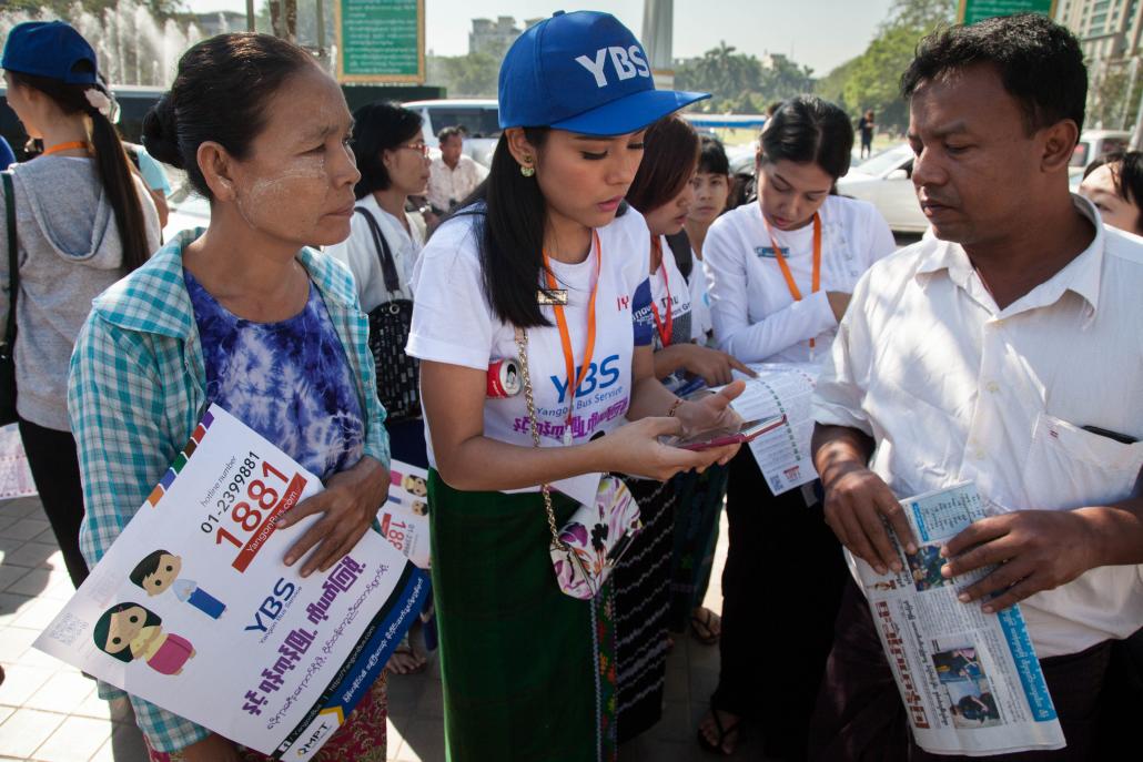 A volunteer offers commuters advice as Yangon's bus network overhaul begins on Monday. (Theint Mon Soe — J / Frontier)