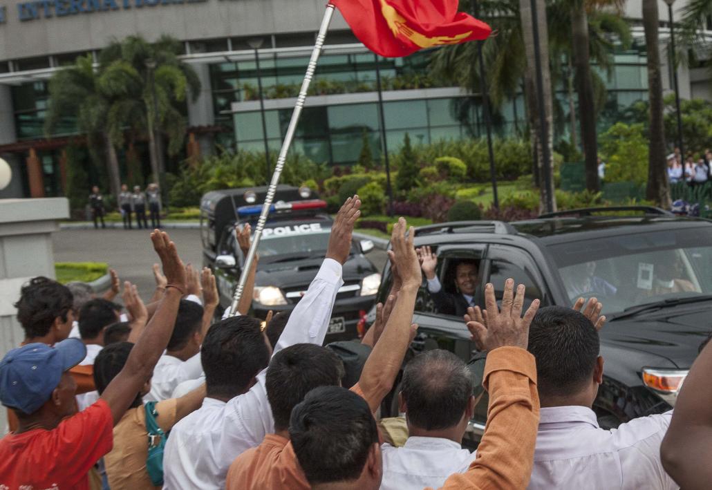NLD members wave to Phyo Min Thein's car as he leaves Yangon Airport on Wednesday. (Theint Mon Soe / Frontier)