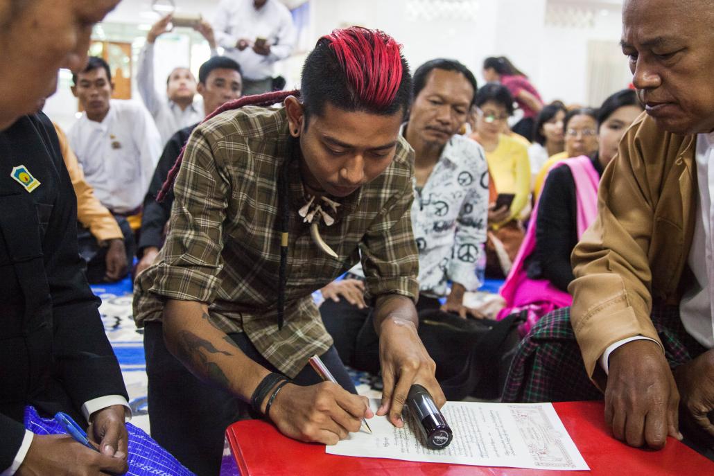 Rebel Riot member Ko Kyaw Kyaw signs the apology on Wednesday. (Theint Mon Soe — J | Frontier)