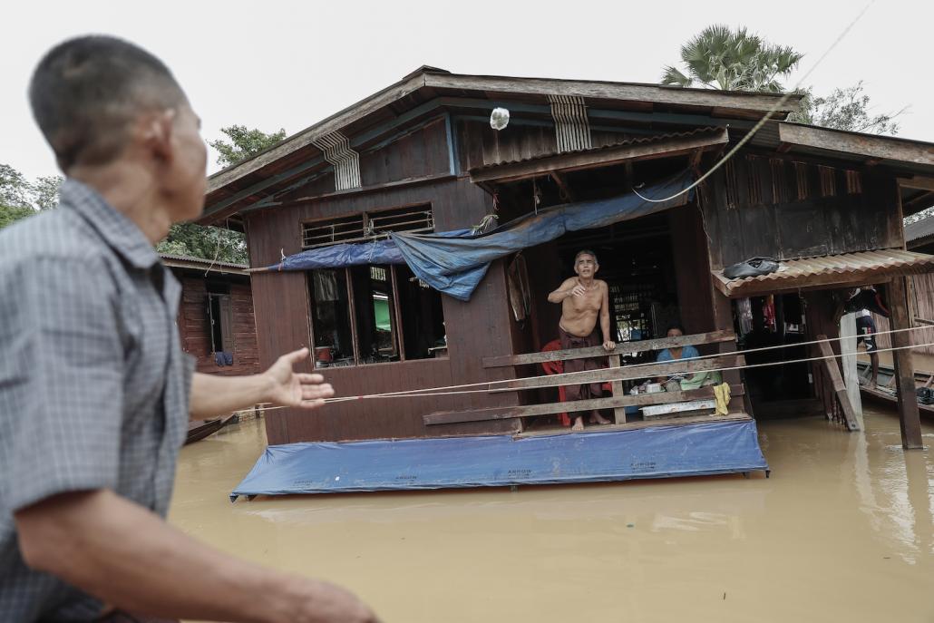 A resident gestures from the second-floor of his flooded home in Nga Pyay Ma village, in Mon State's Kyaikmayaw Township, on August 14. (Nyein Su Wai Kyaw Soe | Frontier)