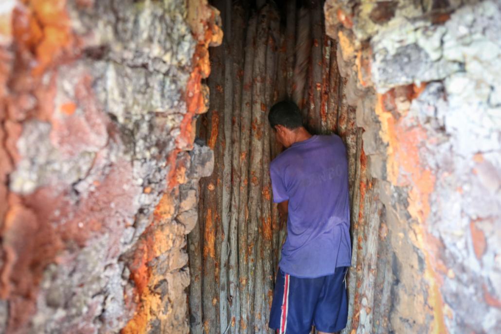 A man stacks mangrove wood for charcoal inside of a kiln near Kyunsu Township in Myanmar. (Victoria Milko | Mongabay)