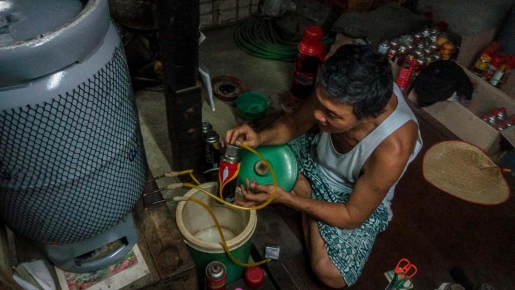 LPG အရောင်းဆိုင်တစ်ခုမှ ဝန်ထမ်းတစ်ဦးက ဆလင်ဒါဘူးအတွင်းသို့ ဓာတ်ငွေ့ဖြည့်တင်းနေစဉ်။ ဓာတ်ပုံ-စတိဗ် တစ်ခ်နာ